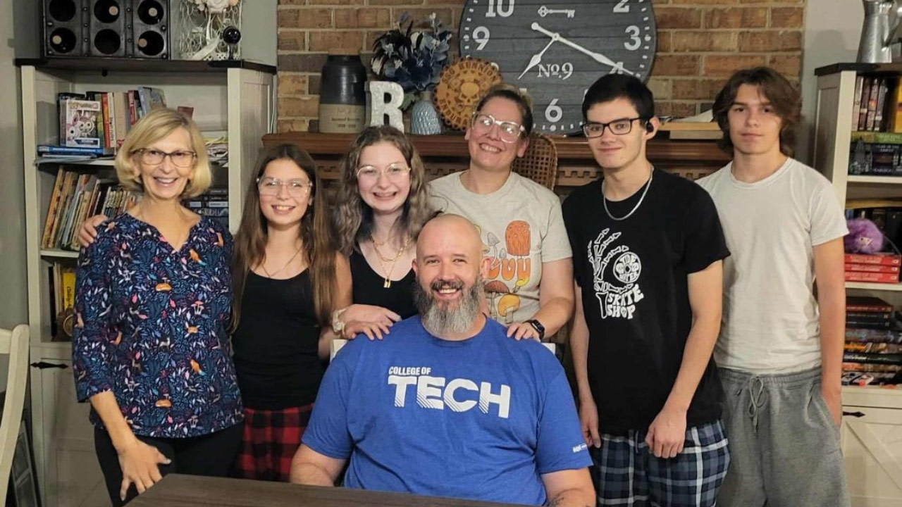 Daniel sitting at home surrounded by his family