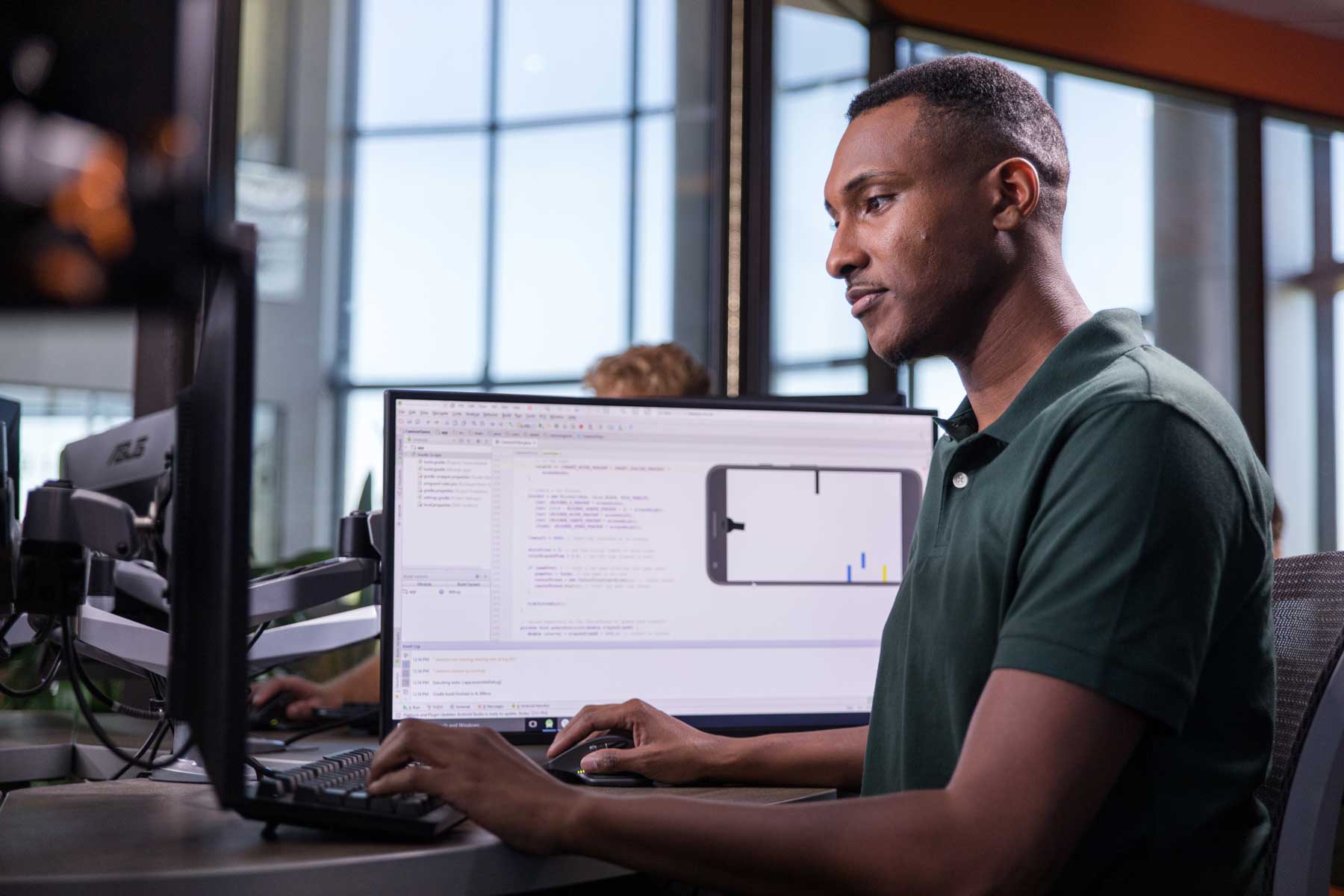 Software development student working at multiple monitors