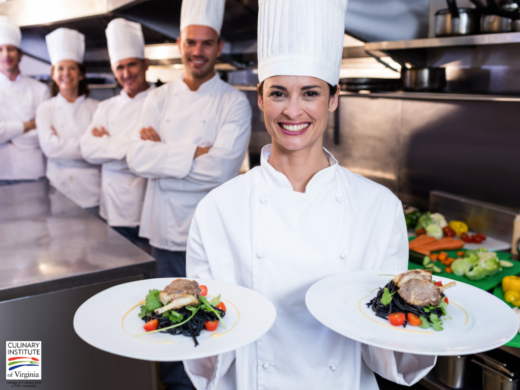 Woman dressed as chef holding out two plates of food.