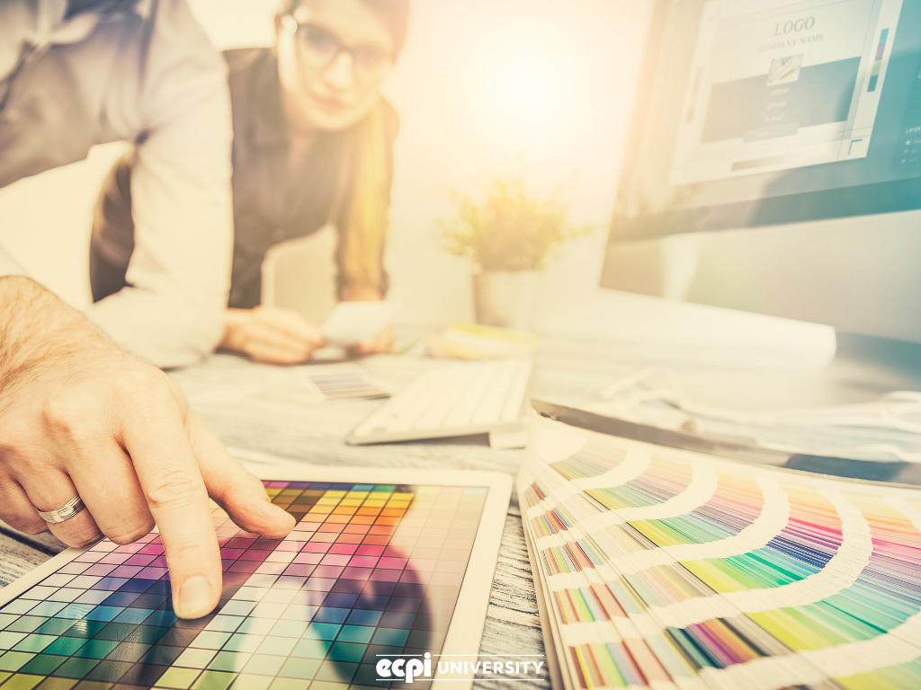 Two people leaning over desk reviewing color choices.